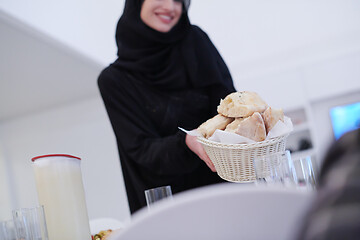 Image showing young muslim girl serving food on the table for iftar dinner