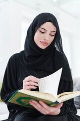 Image showing young muslim woman reading Quran at home
