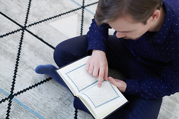 Image showing young muslim man reading Quran at home