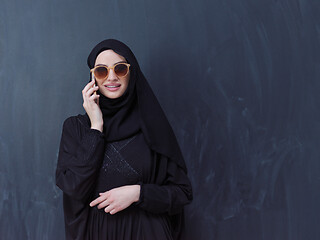 Image showing young muslim woman wearing sunglasses using smartphone