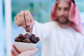 Image showing Muslim family having Iftar dinner eating dates to break feast