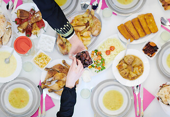 Image showing Muslim family having Iftar dinner eating dates to break feast to