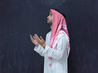 Image showing arabian man making traditional prayer to God, keeps hands in pra