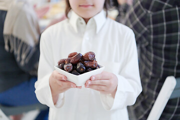 Image showing little muslim boy holding a plate full of sweet dates