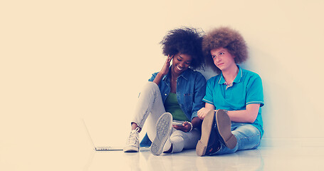 Image showing multiethnic couple sitting on the floor using a laptop and table