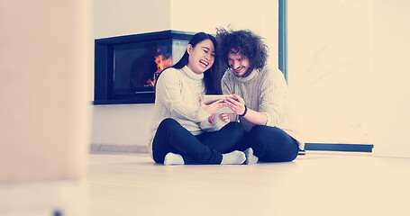 Image showing Young Couple using digital tablet on the floor