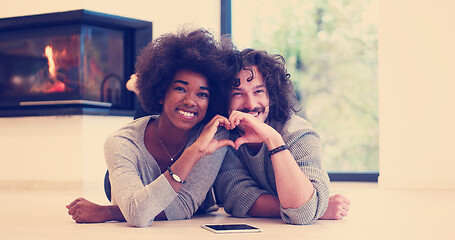 Image showing multiethnic couple showing a heart with their hands on the floor