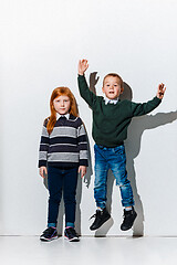 Image showing The portrait of cute little boy and girl in stylish jeans clothes looking at camera at studio