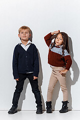 Image showing The portrait of cute little boy and girl in stylish jeans clothes looking at camera at studio