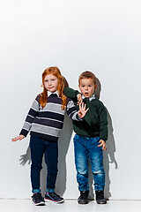 Image showing The portrait of cute little boy and girl in stylish jeans clothes looking at camera at studio