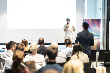 Image showing Businessman in audience standing and asking question to speeker at business conference.