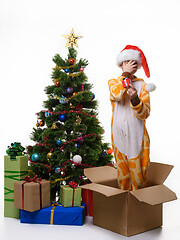 Image showing A girl stands in a box, holds a New Year\'s gift and covers her face with her hand