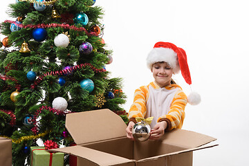 Image showing A girl decorates a Christmas tree and takes out Christmas toys from a box