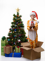 Image showing Cheerful girl holds a gift in her hands and stands in a box for storing Christmas toys