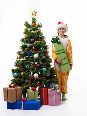 Image showing A girl stands near the Christmas tree with a big New Year\'s gift