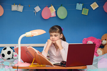 Image showing Girl doing homework at home at the table by the bed