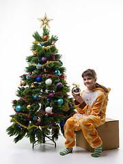 Image showing A girl sits on a box for storing Christmas decorations and holds a ball in her hands