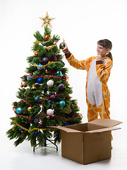 Image showing A girl looks where it is better to hang a ball decorating a Christmas tree