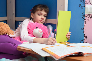 Image showing Girl in the evening does homework at home using a tablet computer.