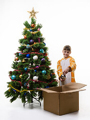 Image showing Girl examines Christmas decorations pulling them out of the Christmas tree