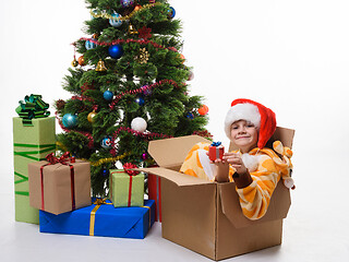 Image showing The girl climbed up and sat in a box decorating a Christmas tree