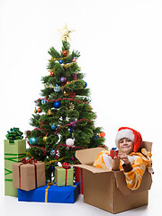 Image showing Girl with a small gift sits in a sick box near the Christmas tree