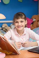 Image showing Smiling girl is doing homework at home.