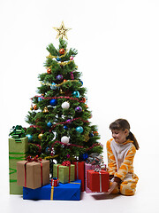 Image showing Girl takes out a gift from under the Christmas tree