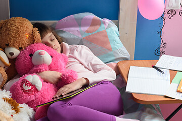 Image showing Girl fell asleep in bed studying remotely and doing homework