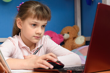 Image showing The girl is remotely studying at home, working in a laptop