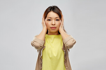 Image showing asian woman closing ears by hands