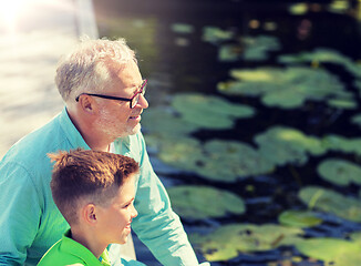 Image showing grandfather and grandson sitting on river berth