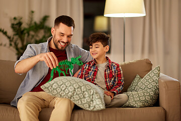 Image showing father and son playing with toy dinosaur at home