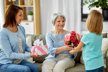 Image showing granddaughter giving flowers to grandmother