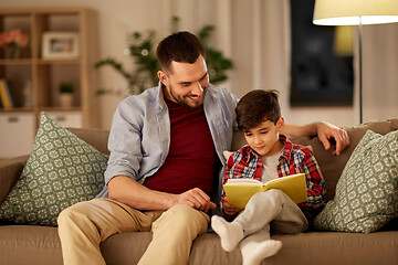 Image showing happy father and son reading book sofa at home