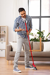 Image showing man with broom cleaning and singing at home