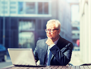 Image showing senior businessman with laptop at city street cafe