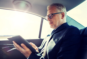 Image showing senior businessman with tablet pc driving in car