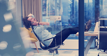 Image showing businessman sitting with legs on desk