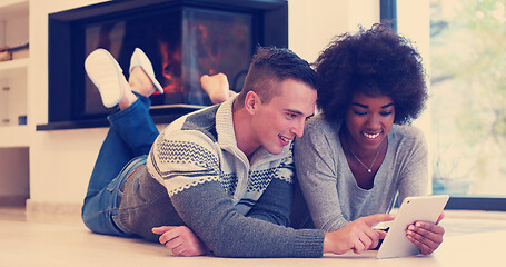 Image showing multiethnic couple using tablet computer on the floor