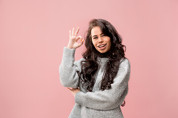 Image showing The happy business woman standing and smiling against pink background.