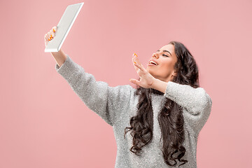 Image showing Portrait of a confident casual girl looking at laptop isolated over pink background