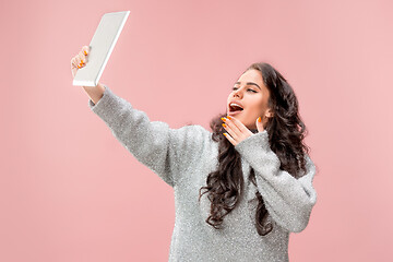 Image showing Portrait of a confident casual girl looking at laptop isolated over pink background