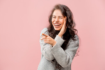 Image showing The young woman whispering a secret behind her hand pink background