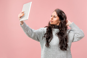 Image showing Portrait of a confident casual girl looking at laptop isolated over pink background