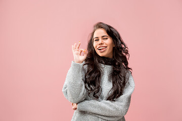 Image showing The happy business woman standing and smiling against pink background.