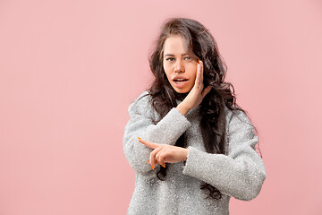 Image showing The young woman whispering a secret behind her hand pink background