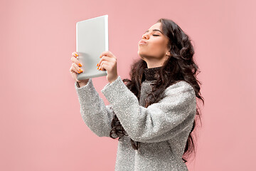 Image showing Portrait of a confident casual girl looking at laptop isolated over pink background