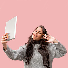 Image showing Portrait of a confident casual girl looking at laptop isolated over pink background