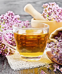 Image showing Tea of oregano in cup with mortar on dark board